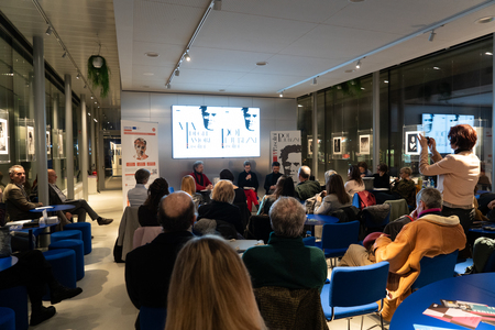 Na fotografiji so slušatelji predstavitve zbirke na prireditvenem prostoru spazioZero v Pordenonu, ki gledajo proti odru, kjer sodelujoči predstavljajo pesniško zbirko. 